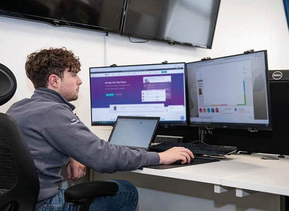 James sitting at his computer looking at 2 screens